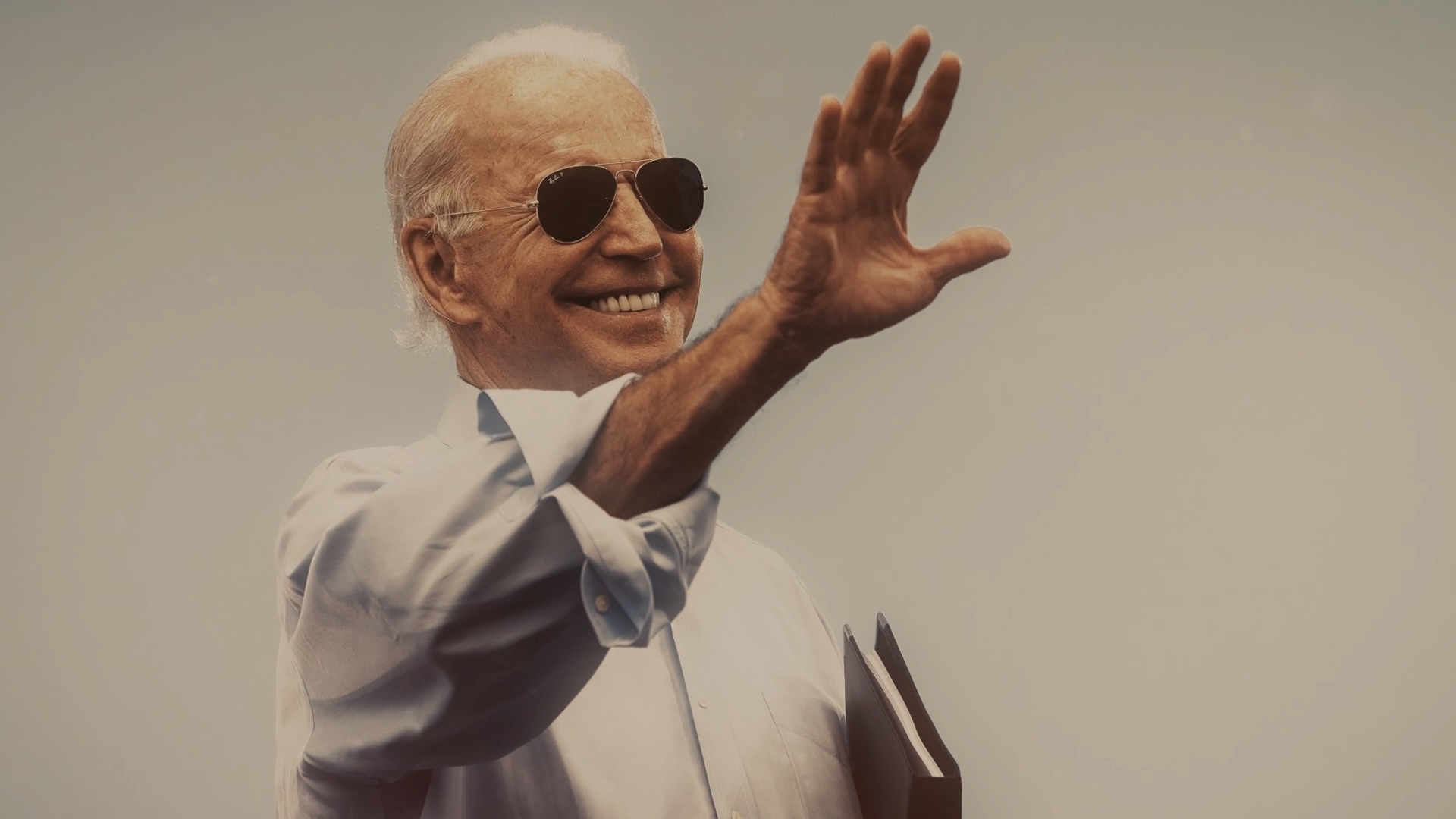 President Biden wearing aviators waves to someone not pictured
